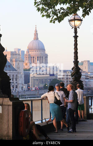 Persone che passeggiano lungo la riva sud su una calda sera d'estate, la Cattedrale di St Paul e dietro, a Londra, Regno Unito Foto Stock