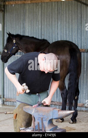 Soldier che fa una bambola di canna con i bambini tradizionalmente vestiti da La Cavalleria domestica che fa una scarpa posteriore per il suo cavallo Foto Stock