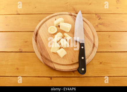 Pezzi di trito di materie pastinaca con un coltello da cucina affilato su di un tagliere di legno Foto Stock