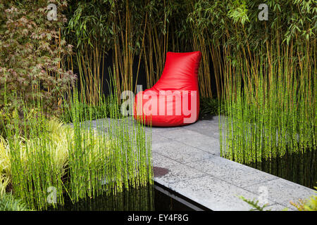 Hard Landscaping in show Garden; Floral Garden Seat e erbe Restios intorno ad un laghetto, e un sedile di plastica rossa a Tatton Park, Cheshire, Regno Unito 21 luglio, 2015. Corsi d'acqua e corsi d'acqua su misura, un design prodotto   UN angolo tranquillo al RHS Flower Show. Foto Stock