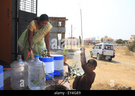 Solapur, India. Xx Febbraio 2014. 20 feb 2014, Solapur, INDIA:.Promodini il giovane figlio aiutarla a eseguire l'acqua shop.Promodini Jhamble corre l'acqua filtrata shop fornite da Eureka Forbes per la fornitura di acqua potabile filtrata per la popolazione rurale di un villaggio vicino Viratnagar Solapur.economicamente i mercati dei paesi poveri nella baraccopoli urbane & villaggi rurali in India stanno diventando sempre più importanti per le grandi società multinazionali come loro obiettivo la domanda di acqua dolce.Circa 96 milioni di persone in India non hanno accesso ad acqua pulita e più di 186000 bambini al di sotto dei cinque anni muoiono da d Foto Stock