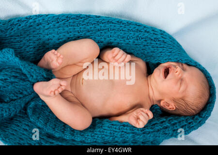 Close up carino White New Born Baby giacente in prono sul panno di cotone bianco con bocca aperta Foto Stock