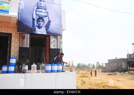 Solapur, India. Xx Febbraio 2014. 20 feb 2014, Solapur, INDIA:.Promodini il giovane figlio, Ajay, attende per rurale di clienti presso il negozio di acqua.Promodini Jhamble corre l'acqua filtrata shop fornite da Eureka Forbes per la fornitura di acqua potabile filtrata per la popolazione rurale di un villaggio vicino Viratnagar Solapur.economicamente i mercati dei paesi poveri nella baraccopoli urbane & villaggi rurali in India stanno diventando sempre più importanti per le grandi società multinazionali come loro obiettivo la domanda di acqua dolce.Circa 96 milioni di persone in India non hanno accesso ad acqua pulita e più di 186000 bambini al di sotto di Foto Stock