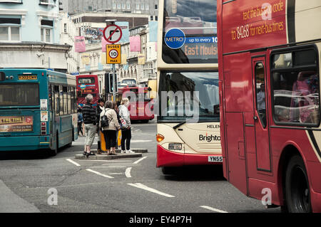 Pedoni che si trovano su un'isola di sicurezza circondata da numerosi autobus a Brighton, Regno Unito dal 2012 Foto Stock