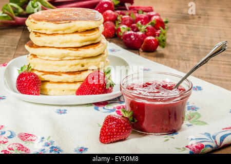 Pila di frittelle sul piatto con fragole e rabarbaro marmellata Foto Stock