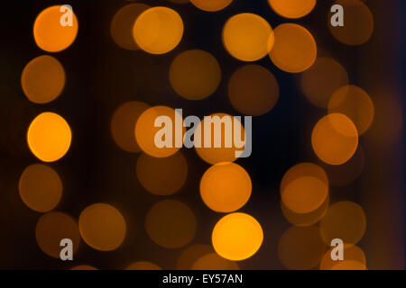 Scintillante di luci di colore arancione con un buio torna sfondo usando un defocalizzata bokeh di fondo tecnica di stile Foto Stock