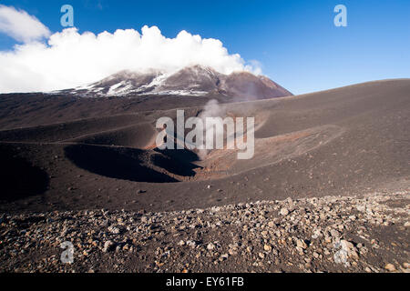 Vulcano cratere fumante sul lato dell'Etna Sicilia Italia in nero campo di lava. Foto Stock