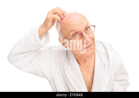 Uomo Senior in un accappatoio bianco il controllo dei suoi capelli isolati su sfondo bianco Foto Stock