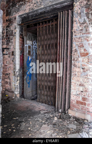 Concertina cancelli di metallo su un vecchio ascensore con graffiti sulle pareti e sfald vernice sui mattoni Foto Stock