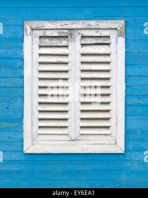 Vecchia finestra di bianco con persiane di legno sulla parete blu di schede madri. Foto Stock