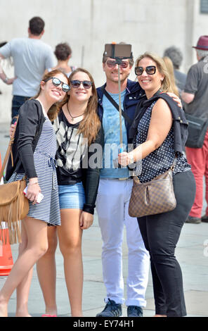 Londra, Inghilterra, Regno Unito. Famiglia in Trafalgar Square di scattare una foto con un bastone selfie Foto Stock