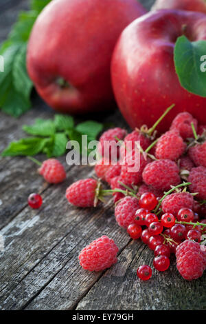 Ribes rosso, rasberry e mele rosse sul vecchio tavolo in legno, mix di colore rosso vitamine concept Foto Stock