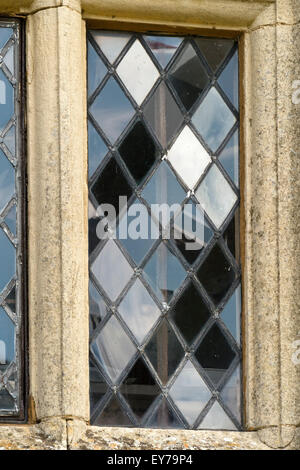 Riflessi in lastre di vetro a forma di diamante di una vecchia finestra con piombo con mulloni di pietra, Rockingham, Northamptonshire, Inghilterra, UK Foto Stock