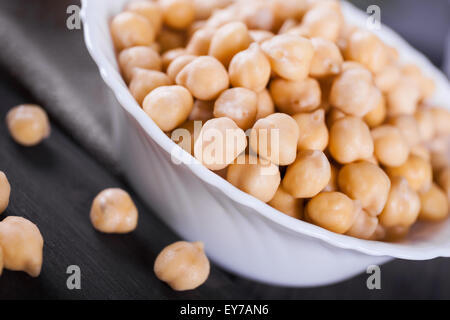 Materie oro bagnato i ceci in una terrina sulla tavola di legno, sano cibo vegan con un sacco di proteina, macro shot, il fuoco selettivo Foto Stock