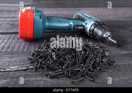 Pila di viti nere e cacciavite closeup su sfondo di legno Foto Stock