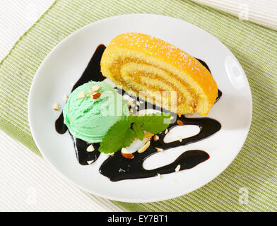 Fetta di Swiss roll dolce con sorbetto verde e salsa al cioccolato Foto Stock