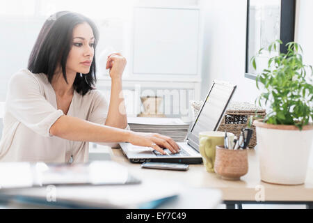 Donna seduta alla scrivania con computer portatile Foto Stock