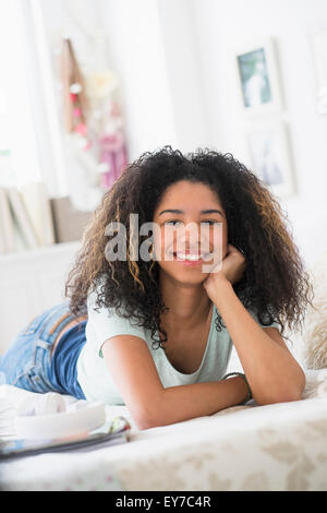 Ritratto di ragazza adolescente (16-17) giacente sul letto Foto Stock