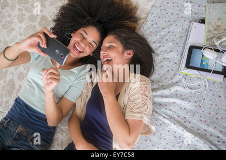 Le ragazze adolescenti (14-15, 16-17) texting in camera da letto Foto Stock