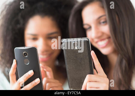 Le ragazze adolescenti (14-15, 16-17) utilizzando i telefoni intelligenti Foto Stock