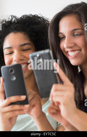 Le ragazze adolescenti (14-15, 16-17) utilizzando i telefoni intelligenti Foto Stock