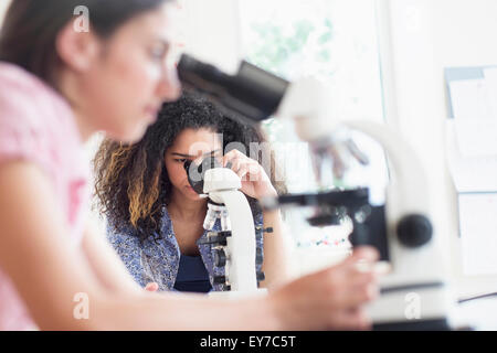 Le ragazze adolescenti (14-15, 16-17) utilizzando il microscopio nella classe di scienze Foto Stock