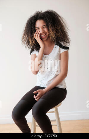 Ritratto di ragazza adolescente (16-17) seduto su uno sgabello Foto Stock