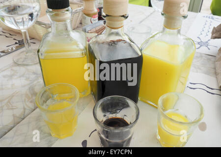 Tre bottiglie e tre bicchieri di liquori su un tavolo. Foto Stock