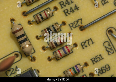 Macro-foto di resistori al carbonio su circuito stampato a foro passante / PCB. Resistenza elettrica, primo piano del circuito, dettaglio di una scheda a circuito stampato Foto Stock
