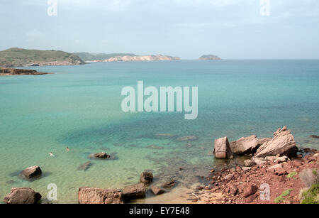 I turisti a nuotare in poco profonde acque cristalline off Cavalleria beach sull'isola di Minorca spagna Foto Stock