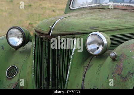 Vecchio arrugginito auto d'epoca in un campo. Foto Stock