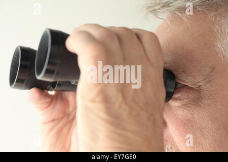 Un vecchio uomo guardando attraverso un vecchio paio di binocoli Foto Stock