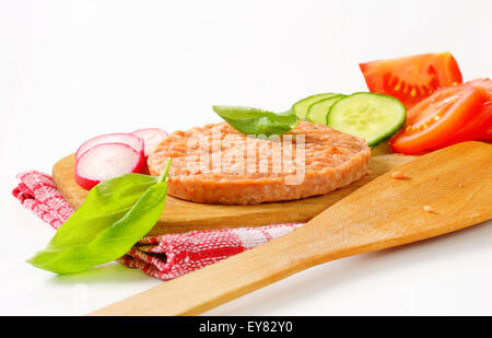 Materie burger patty e verdure a fettine sul bordo di taglio Foto Stock