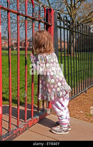 Il Toddler guardando attraverso il parco giochi ringhiere Foto Stock