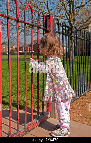 Il Toddler guardando attraverso il parco giochi ringhiere Foto Stock