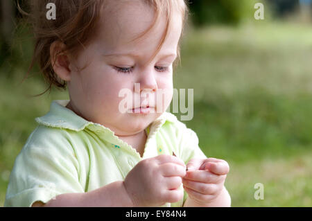 Ritratto di una bambina guardando e giocando con una foglia Foto Stock