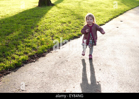 Bambina che corre verso la telecamera nel parco Foto Stock