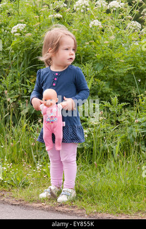 Bambina in piedi tenendo la bambola Foto Stock