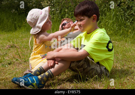 Bambina mettendo la crema solare sulla faccia dei ragazzi Foto Stock