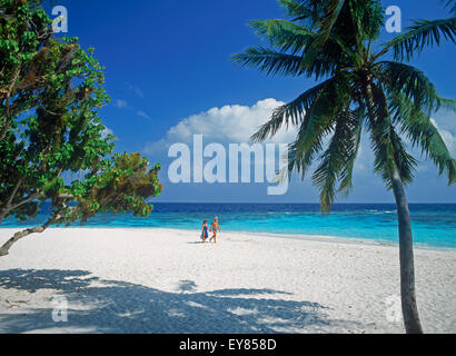 Giovane camminando sulla isola tropicale delle Maldive su spiagge di sabbia bianca sotto i cieli blu accanto a chiare acque aqua Foto Stock