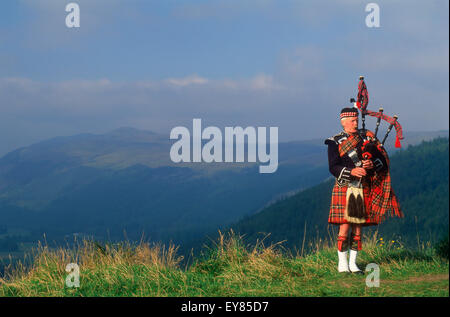 Bagpiper a Loch Ginestra nelle Highlands scozzesi Foto Stock