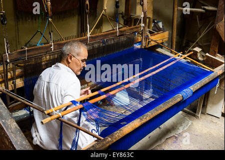 Uomo al lavoro su un telaio di tessitura nel centro storico, Fez el Bali, Fes, Marocco Foto Stock