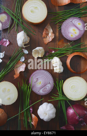 Cipolle, erba cipollina e aglio sparsi sul tavolo di legno per la preparazione del cibo e il concetto di cucina a vista, con applicata retrò stile vintage fil Foto Stock