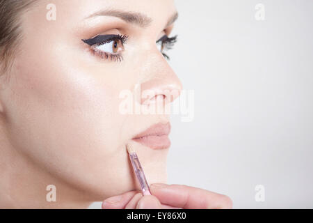 Giovane donna di applicare il make-up sul suo viso Foto Stock