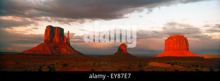 Panoramica di luce del tramonto che si sposta attraverso la Monument Valley tra le nuvole che passa e delle manopole Foto Stock