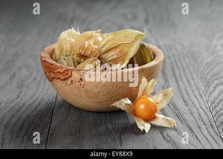 Physalis frutto nella tazza di olive su oak tavolo in legno Foto Stock