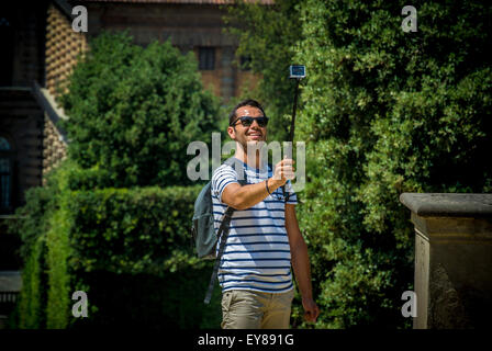 Giovane turista maschile adulto scattando una fotografia di se stesso con un bastone selfie. Foto Stock