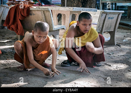 Giocare biglie. Giovane ragazzo monaci buddisti che giocano il gioco dei marmi tradizionali. Thailandia S. E. Asia Foto Stock