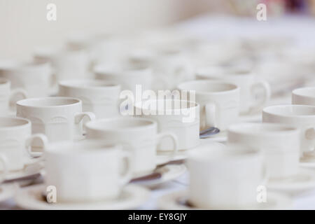 Numerose file di tazze da caffè o tè vuote e piattini disposti su un tavolo in occasione di un evento o di una cerimonia per rinfrescare gli ospiti o i clienti Foto Stock