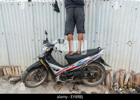 Un pescatore ricreativo in piedi su una motocicletta per pescare su uno stagno situato in un'area chiusa nella zona costiera di Giacarta a Marunda, Jakarta, Indonesia. Foto Stock